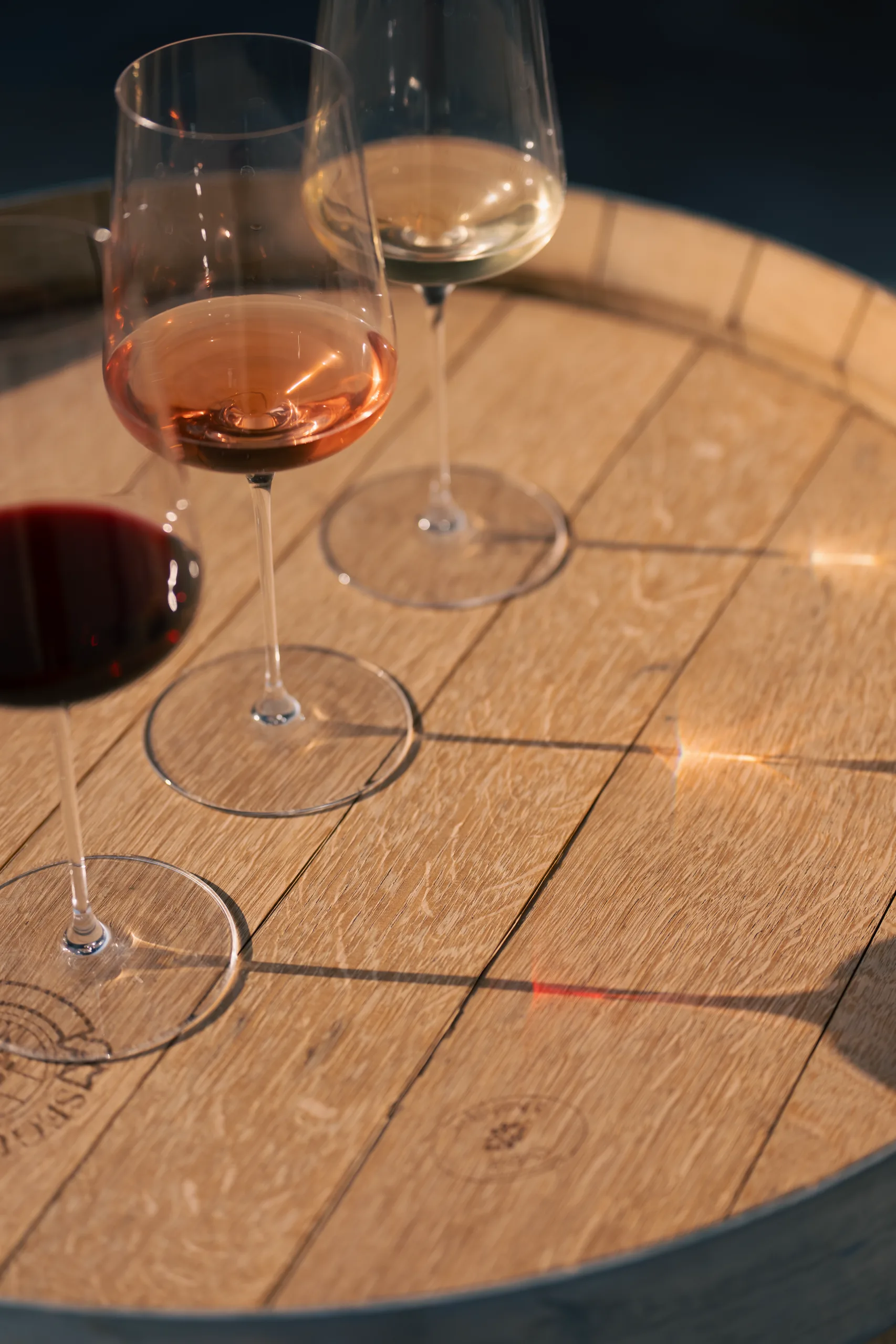Trois verres de vin Mas Rouvier, rouge, rosé, blanc, sur un fût de chêne