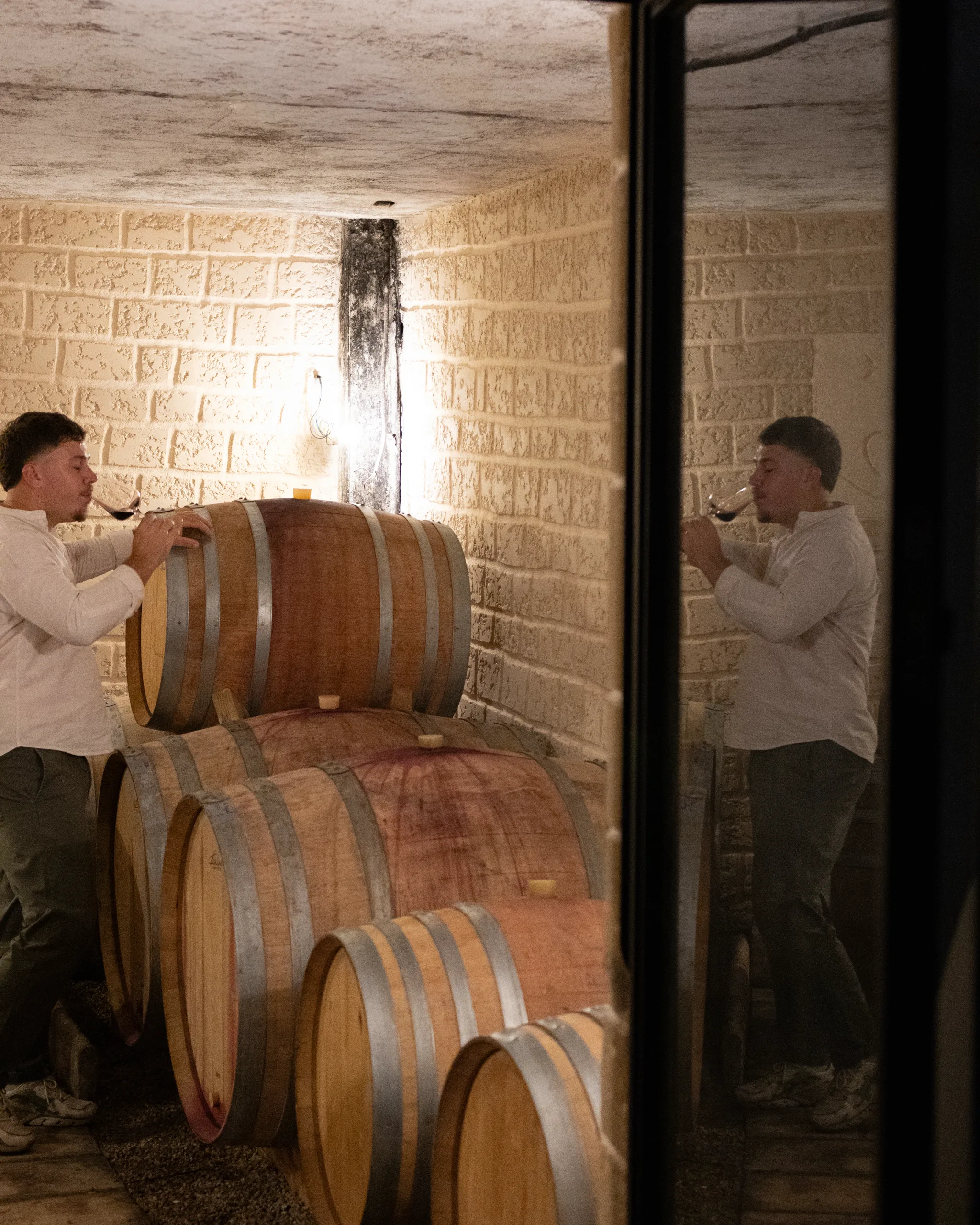 Numa Rouvier dégustant à la cuve, au milieu des fûts du chai